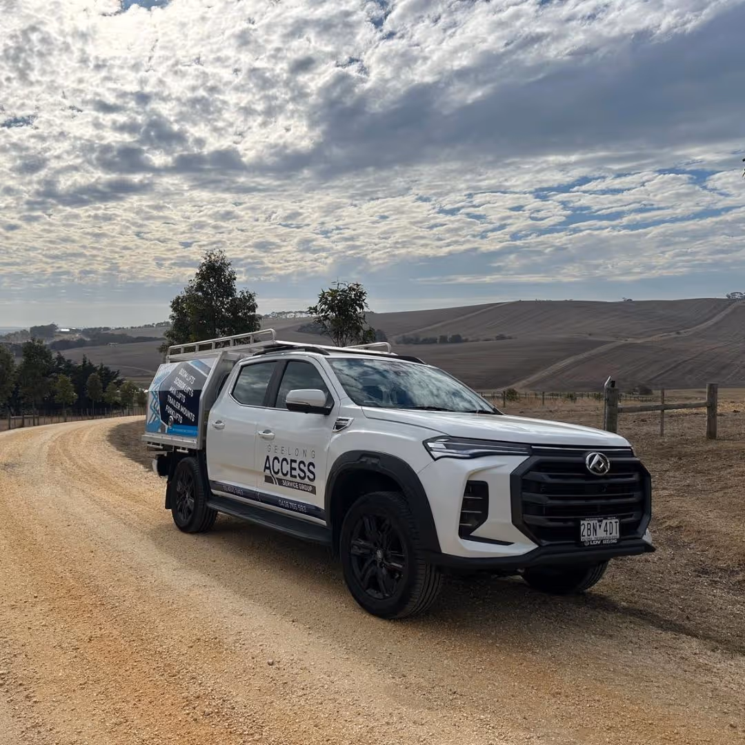 A white utility vehicle is parked on a dirt road in a rural area.