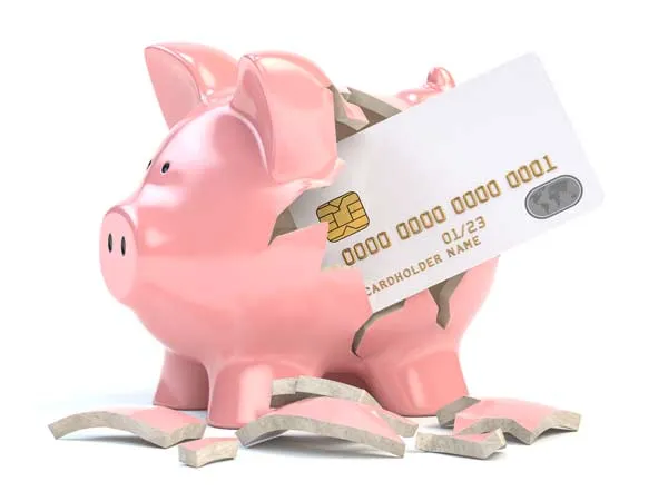 A piggy bank is broken by a credit card inserted into its side.